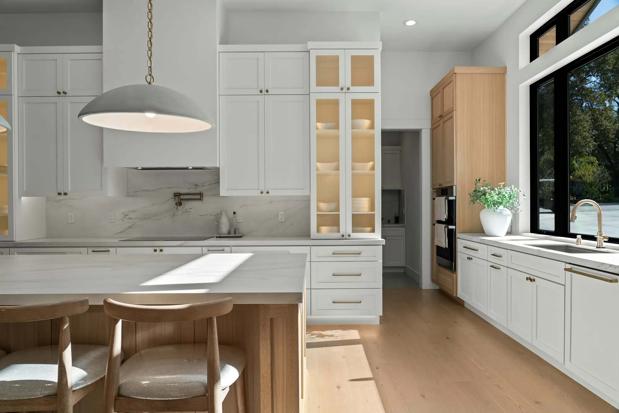 Bright white kitchen with a natural wood island and a large pendant light