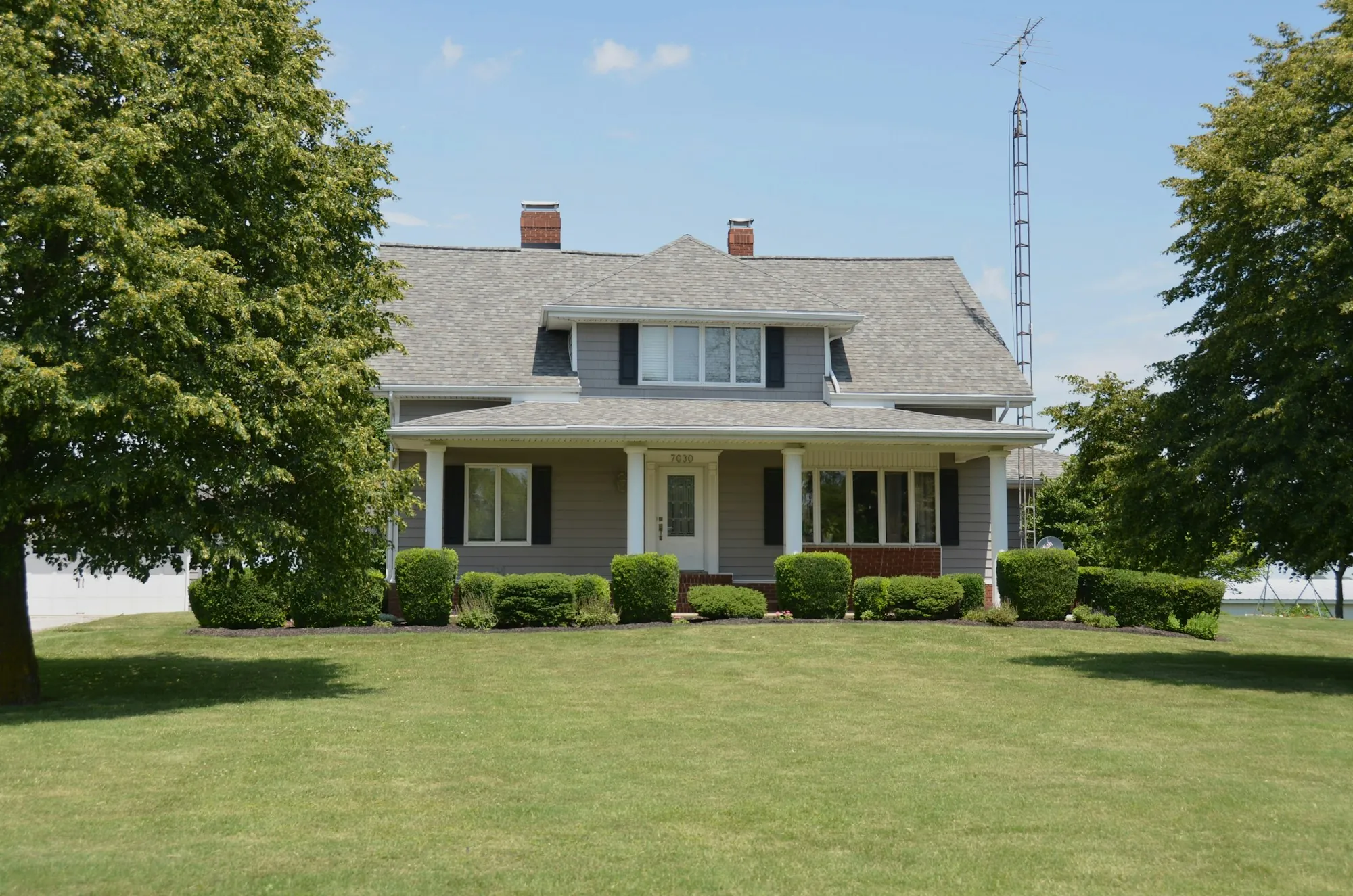 Two-story home with a covered front porch and a wide green lawn