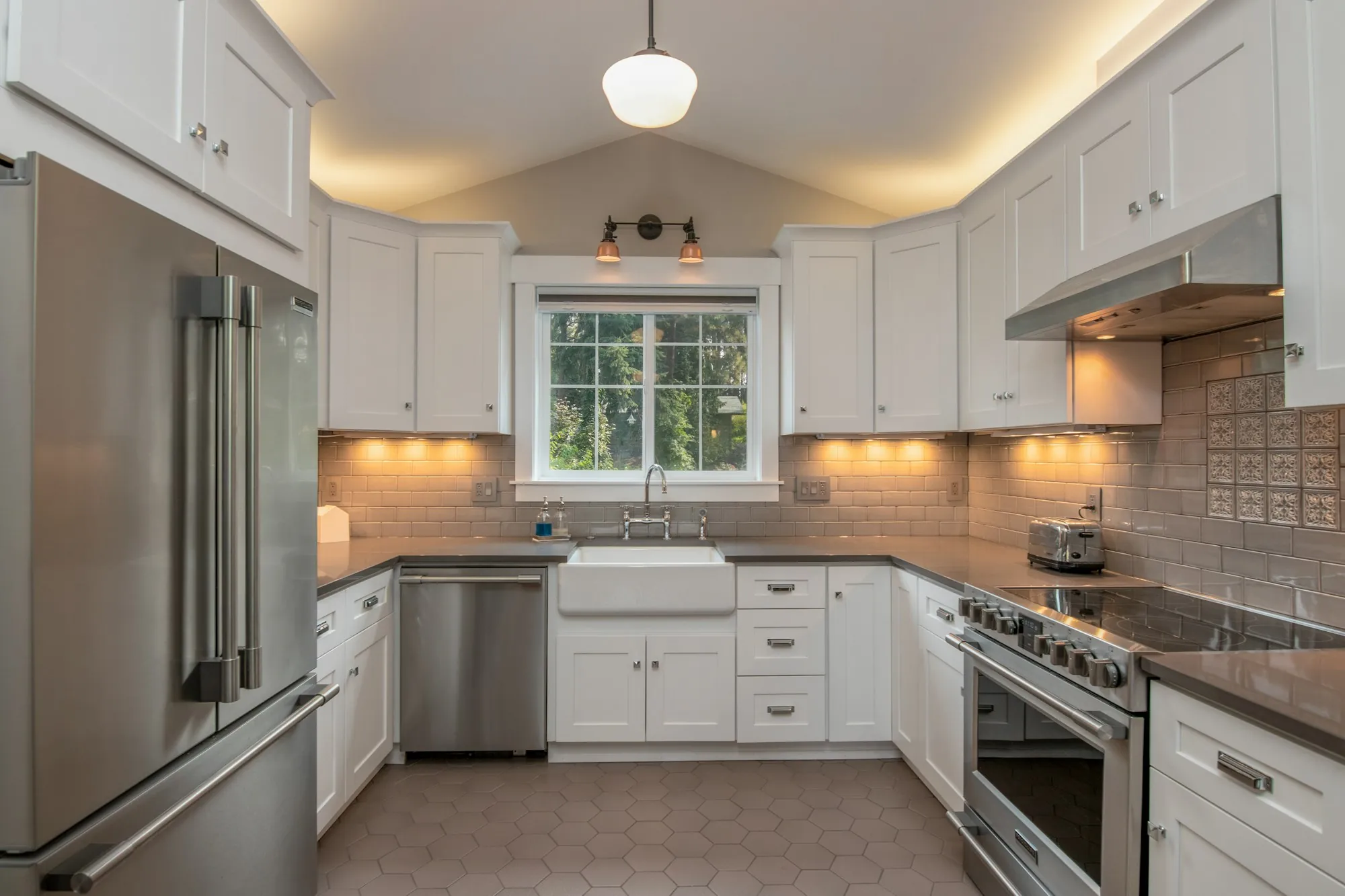 Renovated white shaker kitchen with a farmhouse sink under the window and a tile backsplash