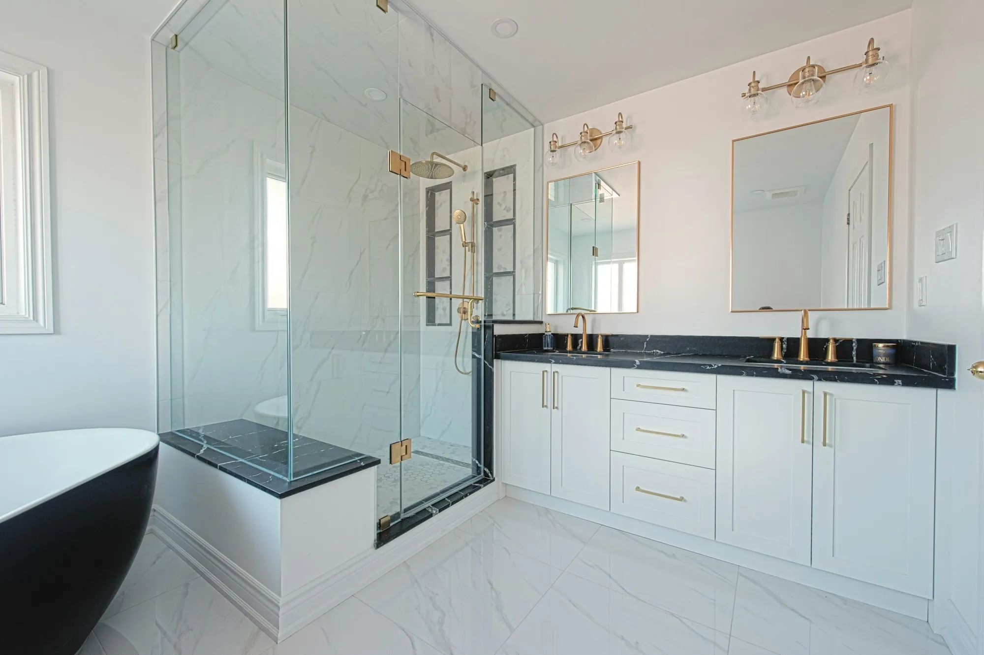Remodeled bathroom with a frameless glass shower and a white vanity with a dark countertop